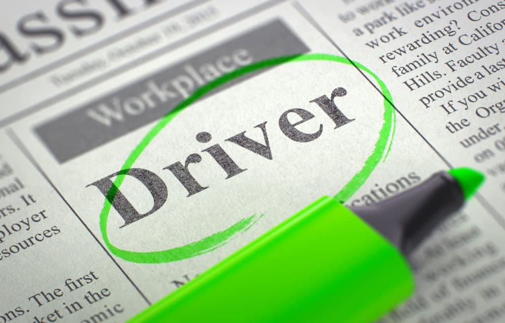 a green marker pointing to the word driver on a newspaper