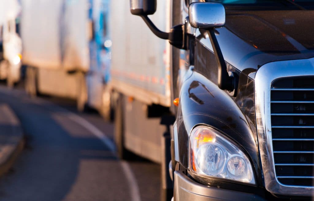 a line of semi trucks driving down a street