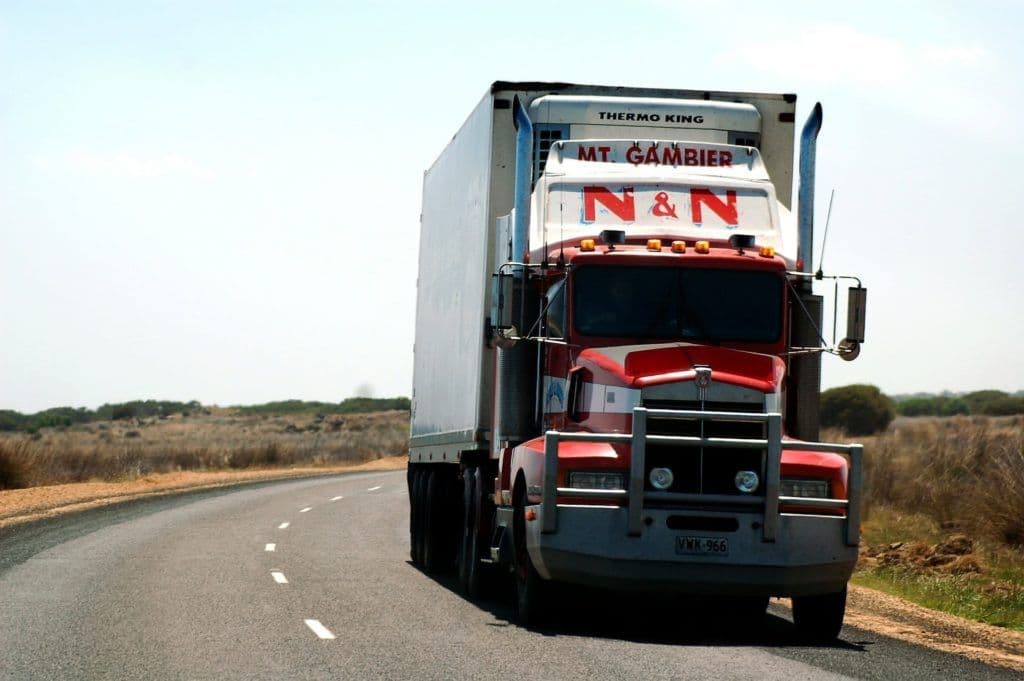 a red and white semi truck driving down a road