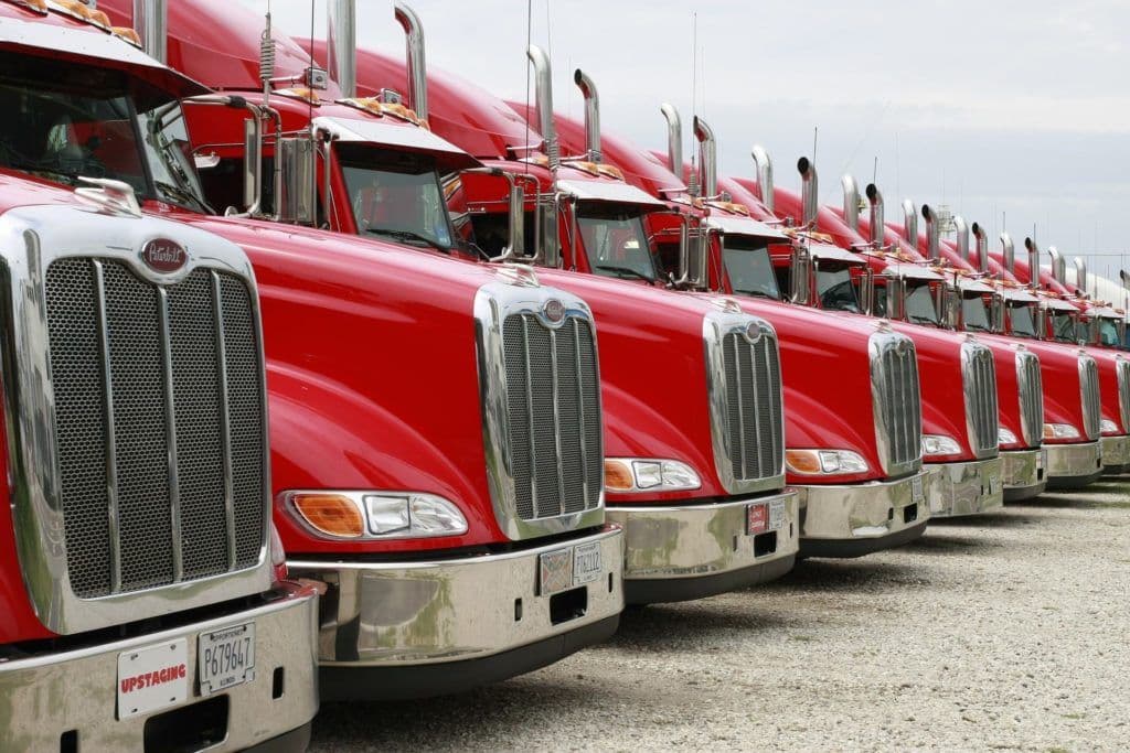 a row of red semi trucks parked next to each other