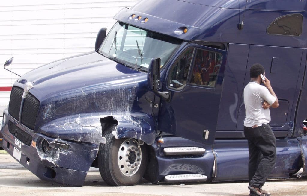 a man standing next to a blue semi truck