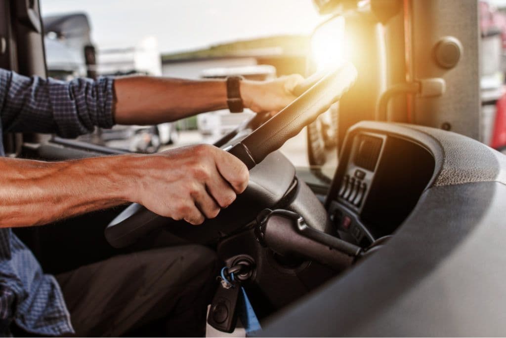 a man driving a truck with a steering wheel