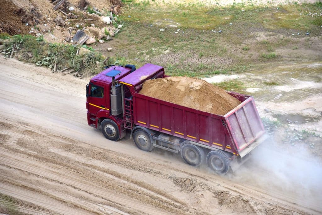 a dump truck driving down a dirt road