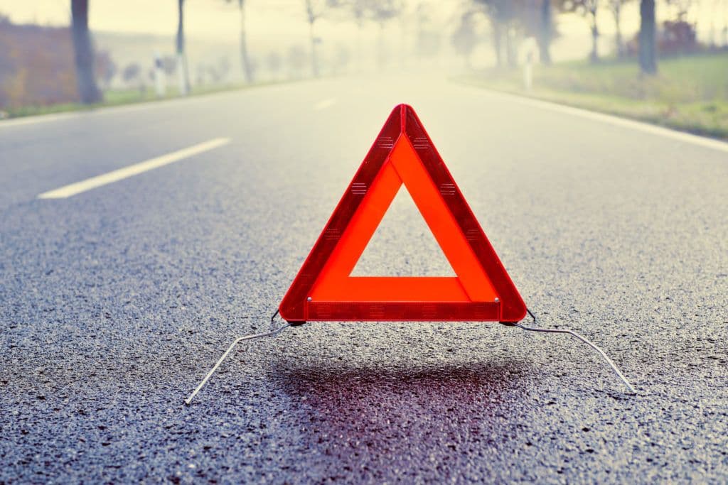 a red triangle sign sitting on the side of a road