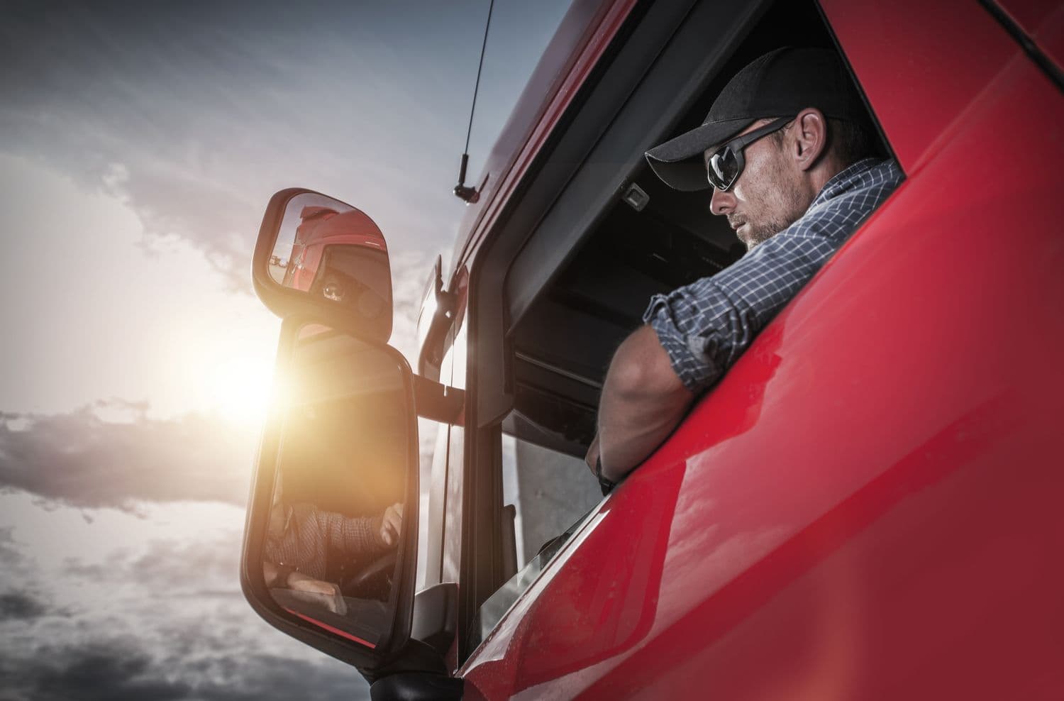 a man is looking out the window of a red truck
