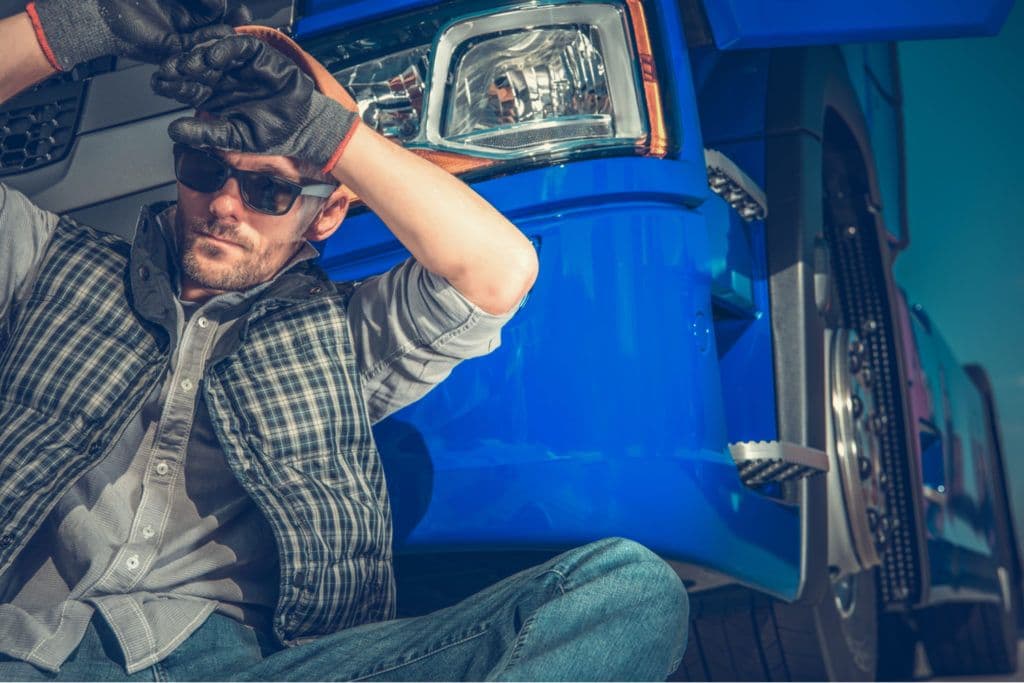 a man sitting on the ground next to a blue truck
