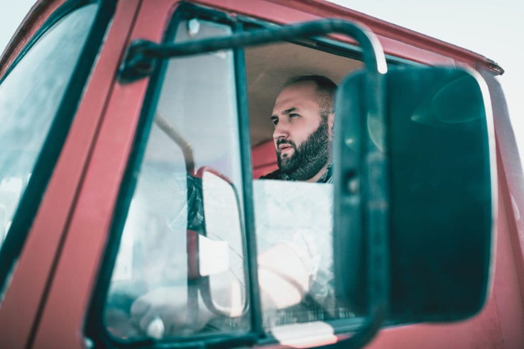 a man is looking out the window of a red truck