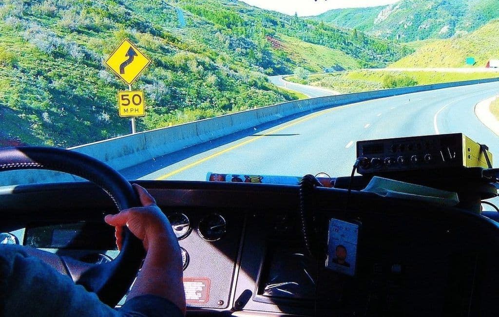 a person driving a car on a road with mountains in the background