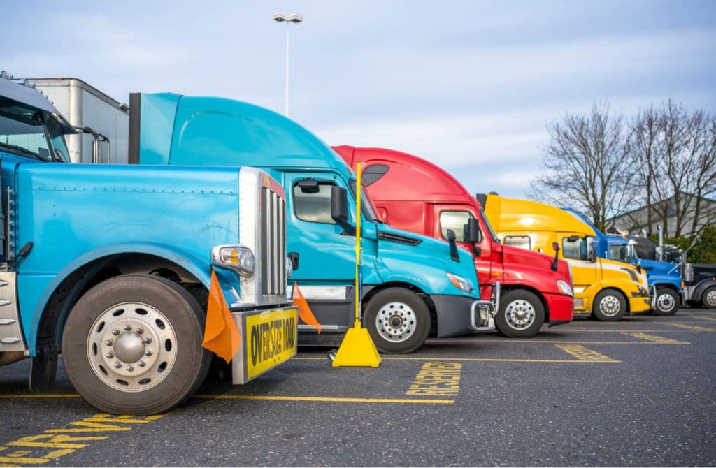 a row of semi trucks parked in a parking lot