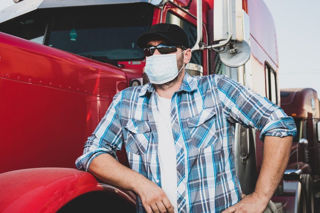 a man wearing a face mask standing next to a red truck