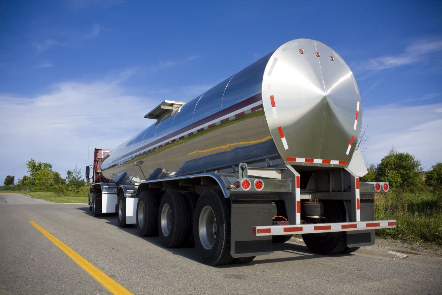a large silver tanker truck driving down a road