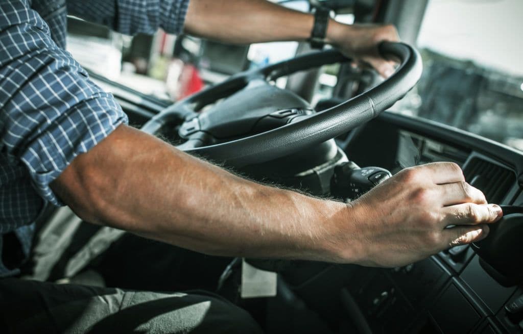 a man driving a truck with a steering wheel