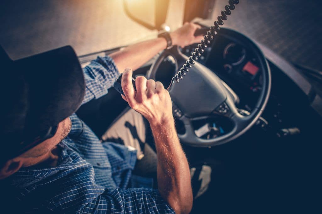 a man sitting in a car holding up an intercom
