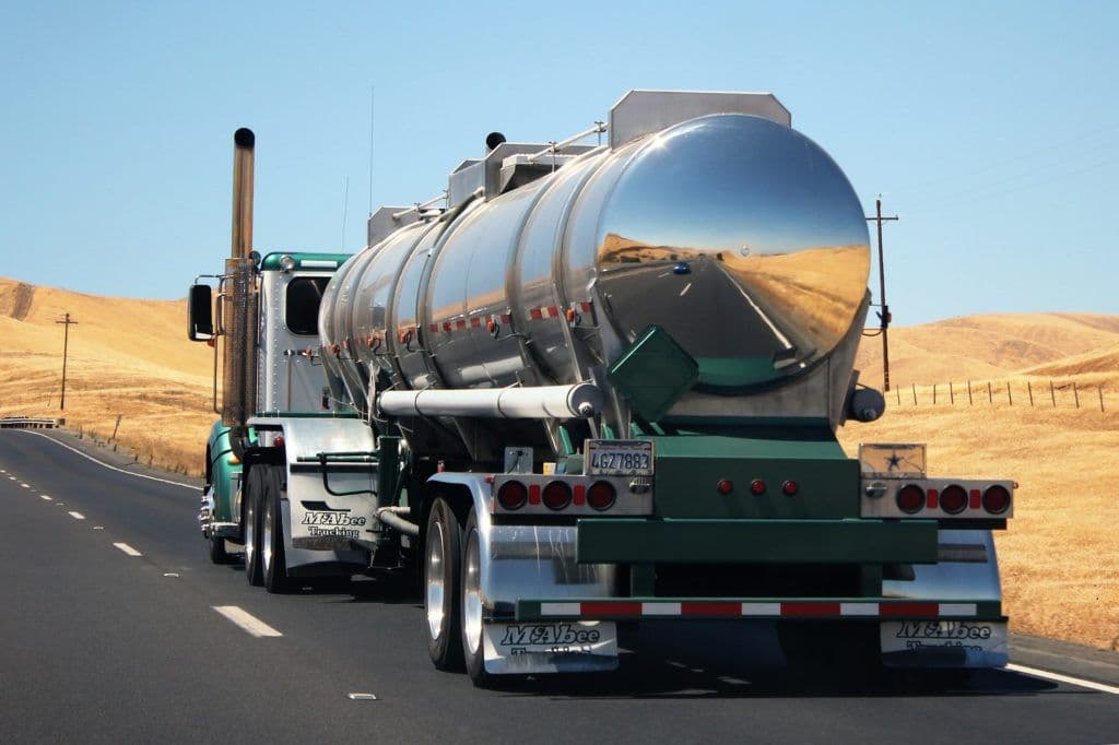 a large truck driving down the street with yellow fields