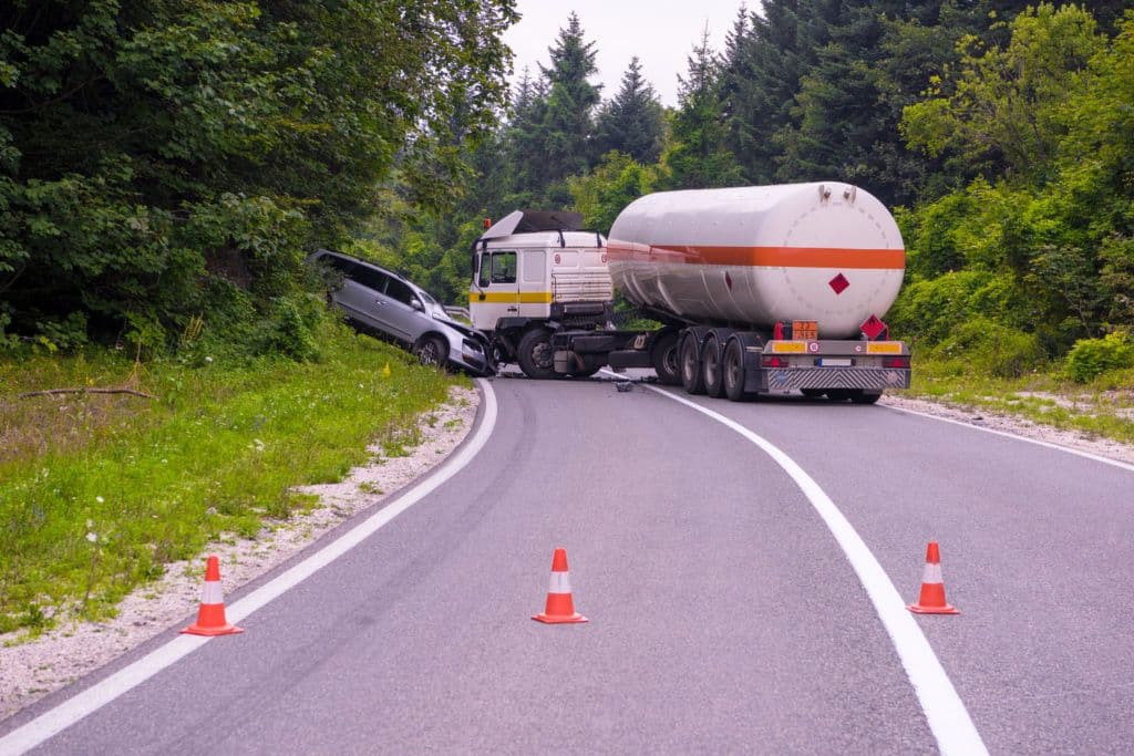 a car is on the side of a road with a tanker truck