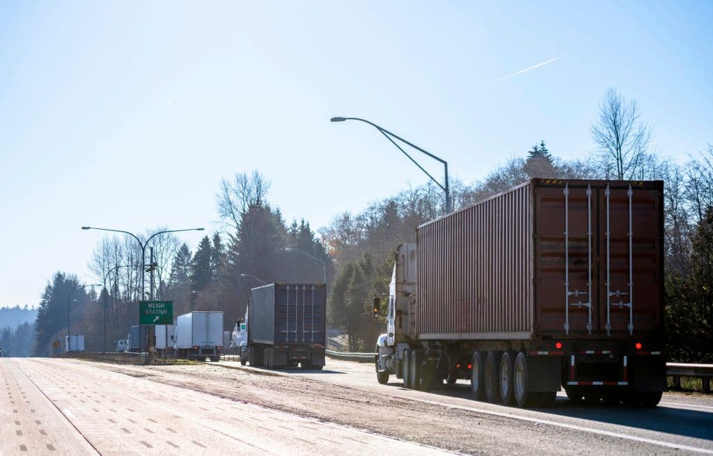 a truck driving down a road next to a forest