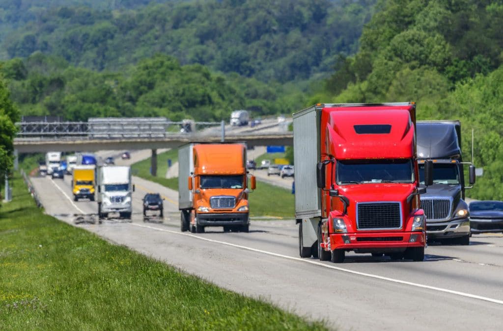 a group of semi trucks driving down a highway