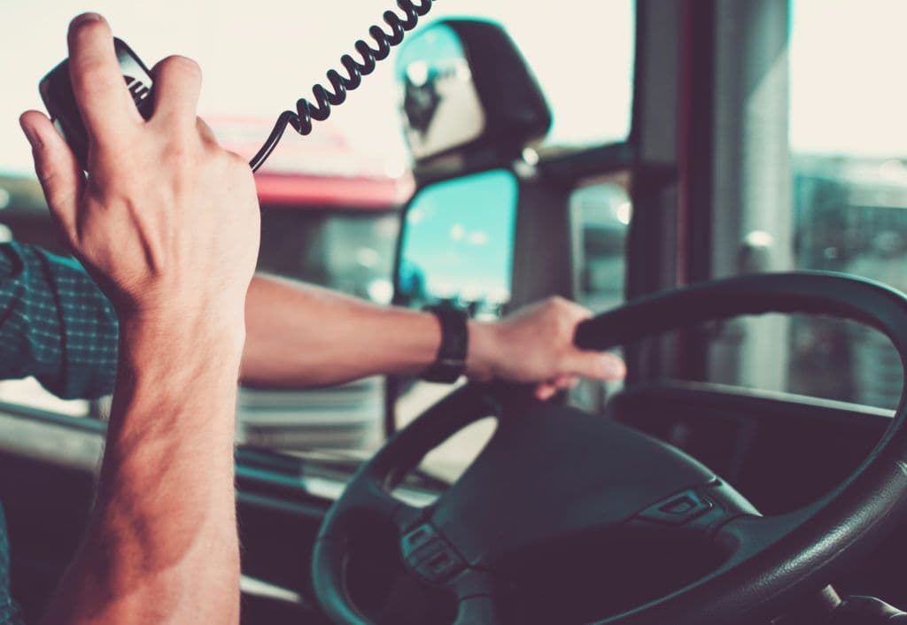 a man driving a bus with his hand on the steering wheel