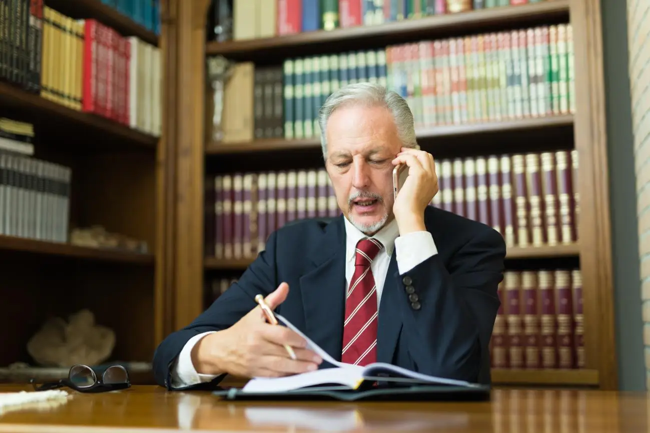 Attorney on the phone reviewing case notes in his office