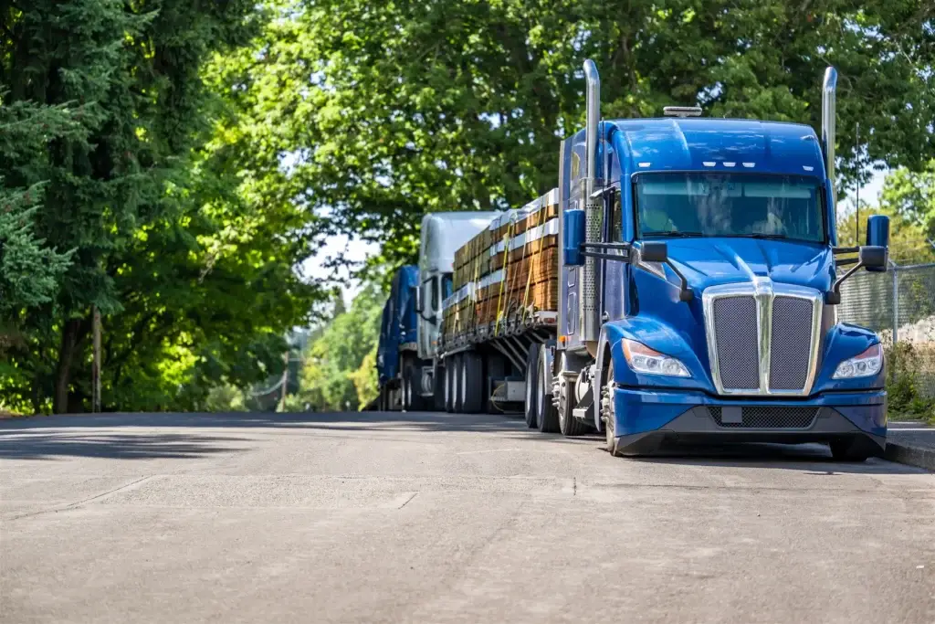 Blue semi-truck with a flatbed trailer loaded with lumber