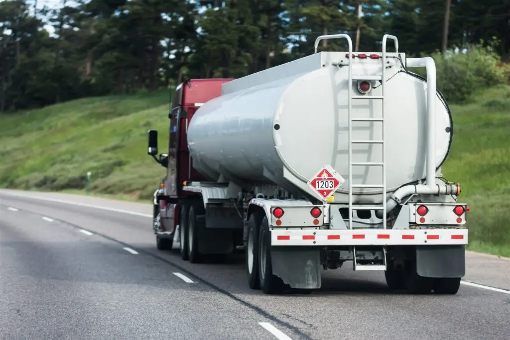 Tanker truck with a hazardous materials placard driving on a highway